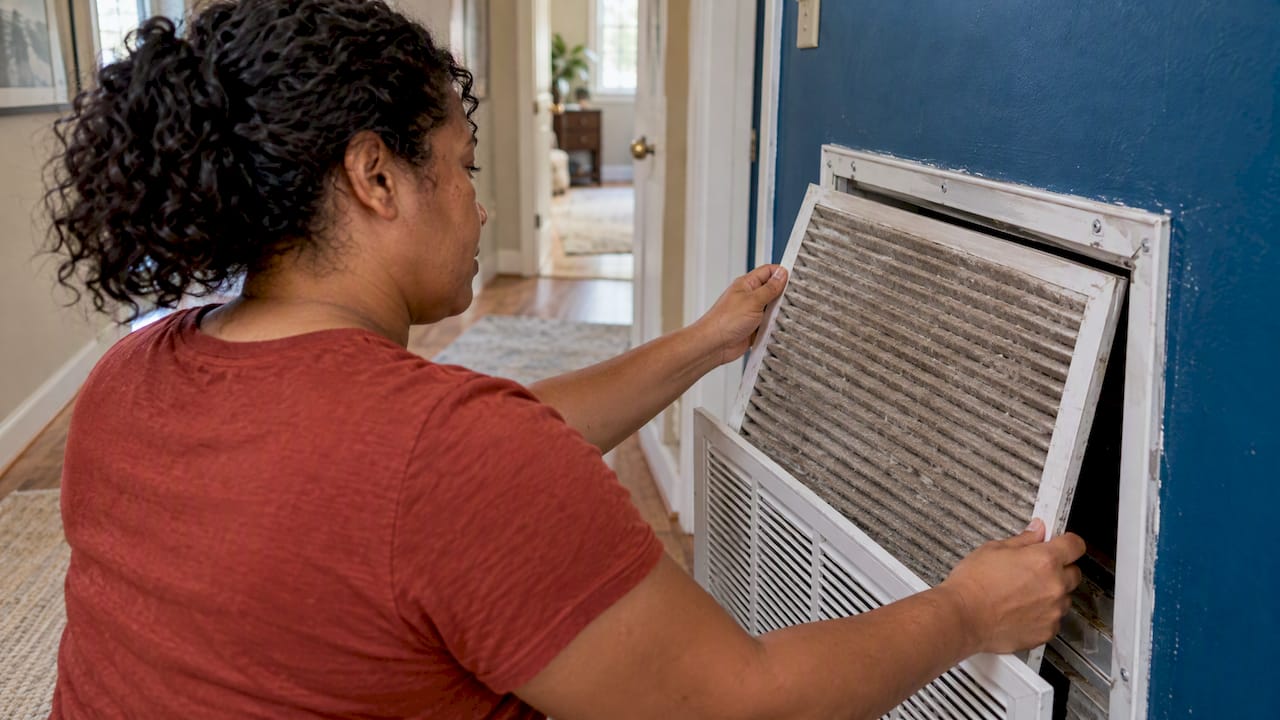 Homeowner removes a dusty air conditioner filter